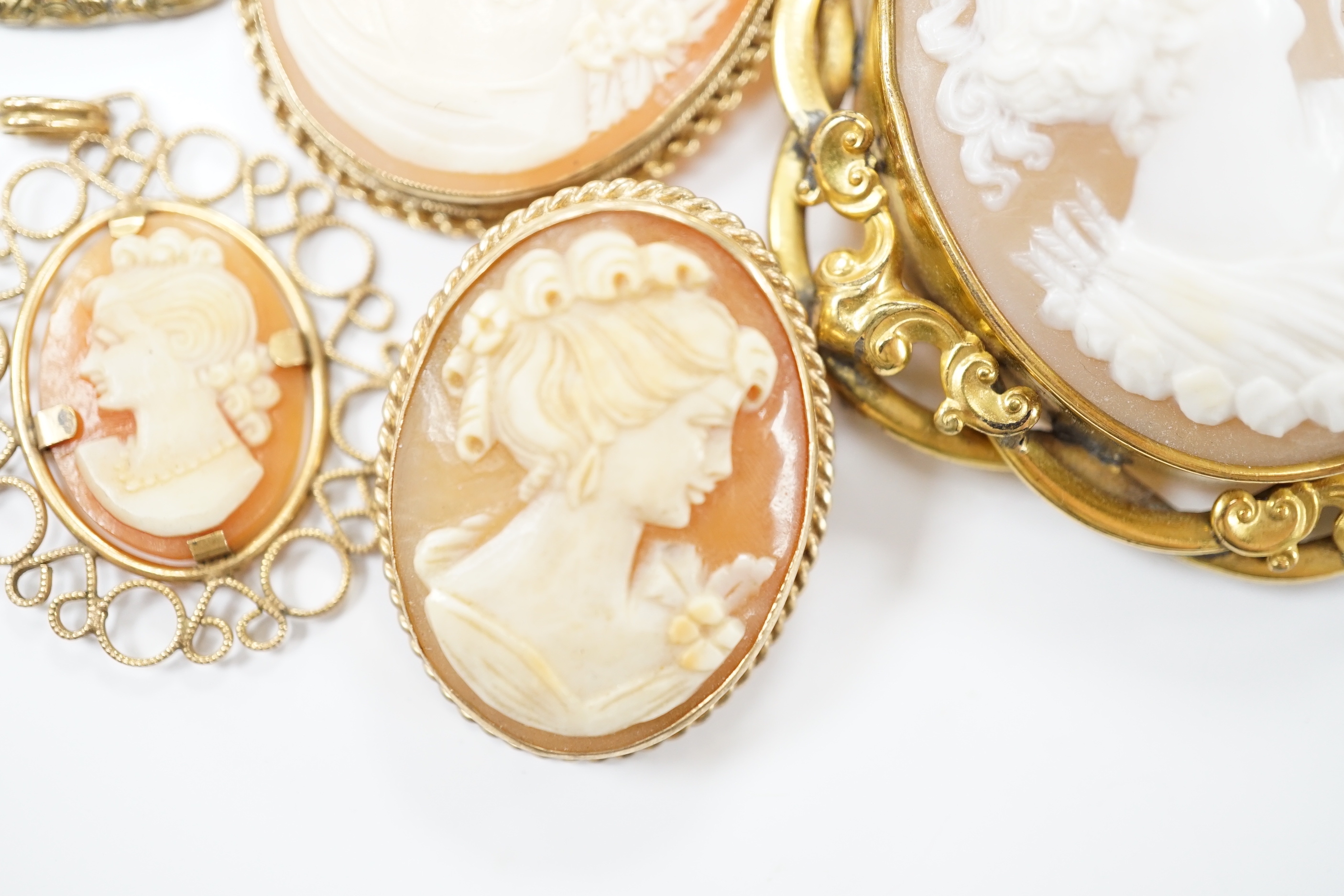 Two modern 9ct gold mounted oval cameo shell pendant brooches, largest 42cm and two other mounted oval cameo shell pendant or brooches and a mourning brooch (a,f,).